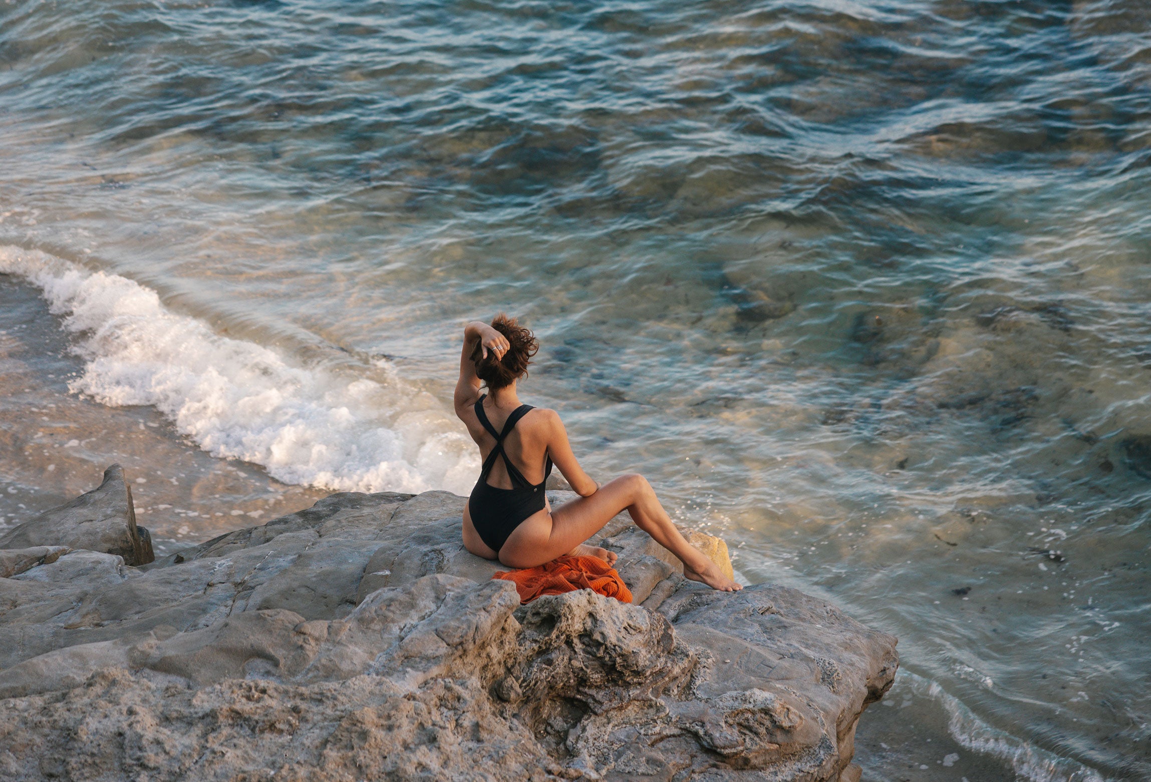 Model on the beach wearing Gemini One Piece in Black