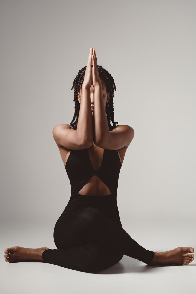 Model wearing Soella Bodysuit in black doing a yoga pose
